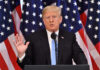 Donald Trump giving a speech with American flags behind.