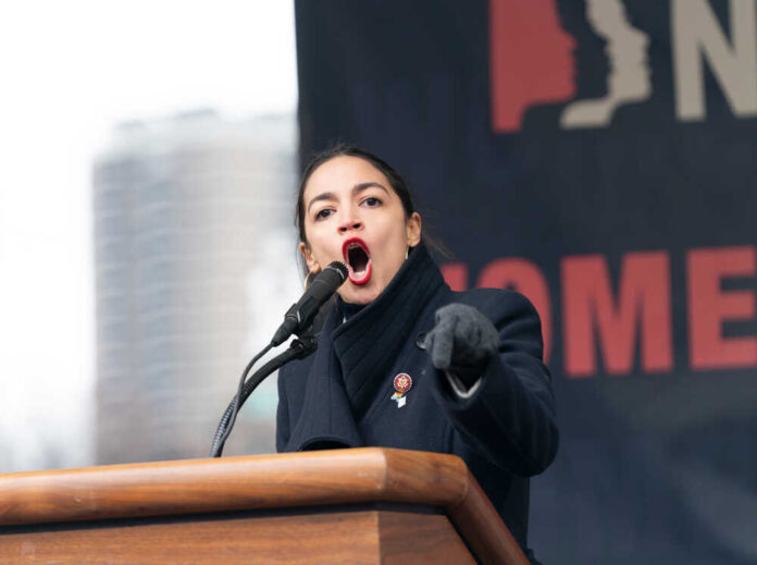 Alexandria Ocasio-Cortez passionately speaking at a podium outside.