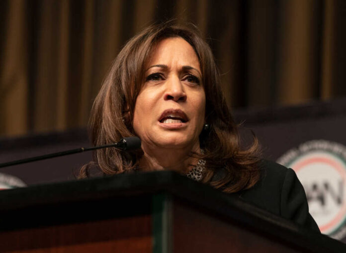 A woman speaking at a podium, looking serious.