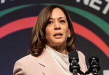 Kamala Harris speaking at an event, microphones in front.