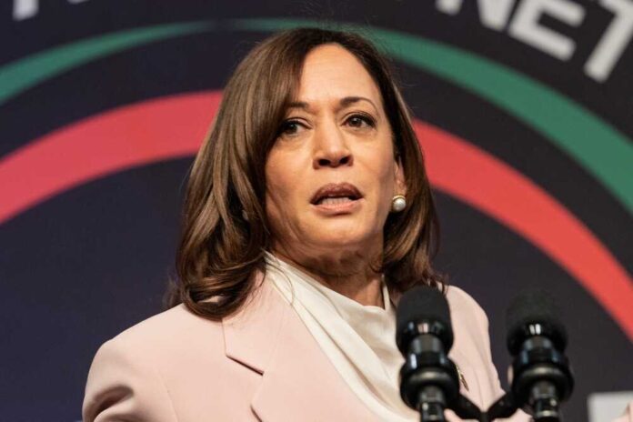 Kamala Harris speaking at an event, microphones in front.