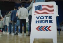 People in line next to Vote Here sign