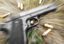 Pistol and bullets on grass with motion blur effect.