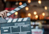 Hand holding a movie clapperboard in studio setting.