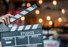 Hand holding a movie clapperboard in studio setting.