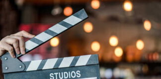 Hand holding a movie clapperboard in studio setting.