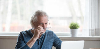 Man with glasses looking at laptop screen.