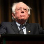 Bernie Sanders in suit speaking at podium.