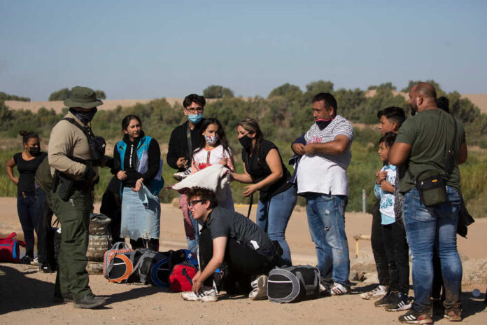 Group of people talking to border patrol officer.