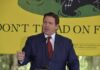 Ron DeSantis speaking in front of yellow Don't Tread sign.