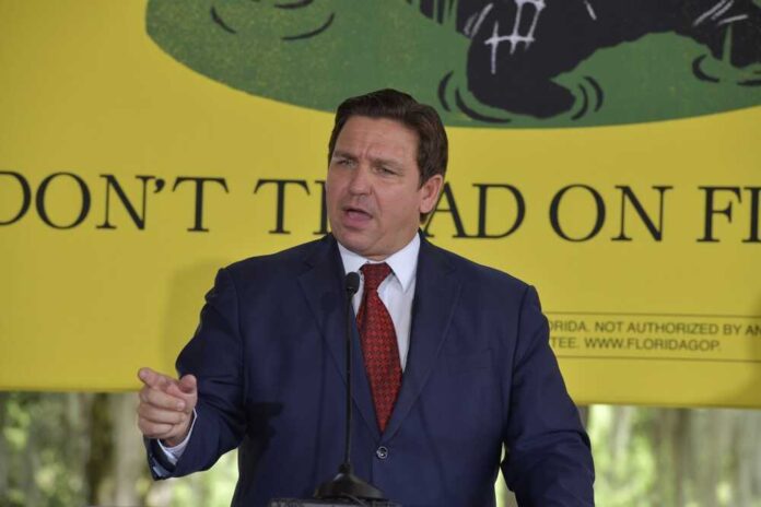 Ron DeSantis speaking in front of yellow Don't Tread sign.