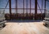 People standing behind a fence on a dusty path.