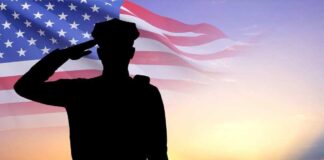 Silhouette saluting soldier, American flag, sunset background.