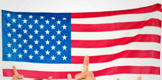 Thumbs up in front of American flag.