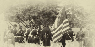 Civil War reenactors marching with U.S. flag.