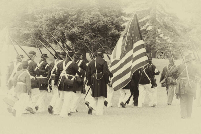 Civil War reenactors marching with U.S. flag.