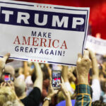 People holding Trump Make America Great Again signs.