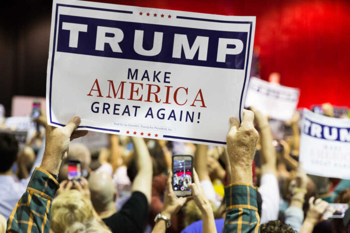 People holding Trump Make America Great Again signs.