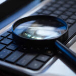 Magnifying glass on a laptop keyboard.