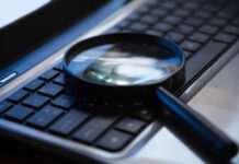 Magnifying glass on a laptop keyboard.