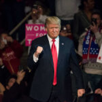 Donald Trump at a rally, surrounded by supporters.