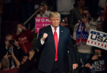 Donald Trump at a rally, surrounded by supporters.