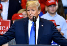 A man in a suit speaking at a rally.