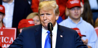 A man in a suit speaking at a rally.