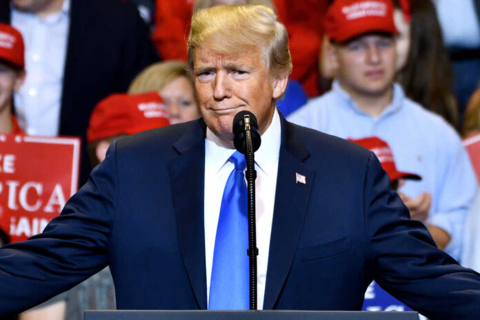 A man in a suit speaking at a rally.