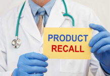 Doctor holding a product recall sign in gloves