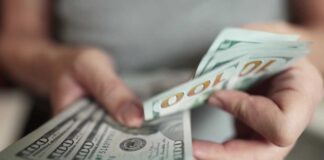 Hands holding stack of one hundred dollar bills