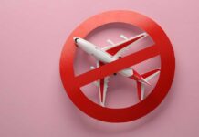 Airplane inside red prohibition sign on pink background.