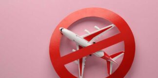 Airplane inside red prohibition sign on pink background.