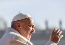 Pope Francis waving outdoors.