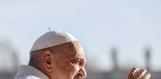 Pope Francis waving outdoors.