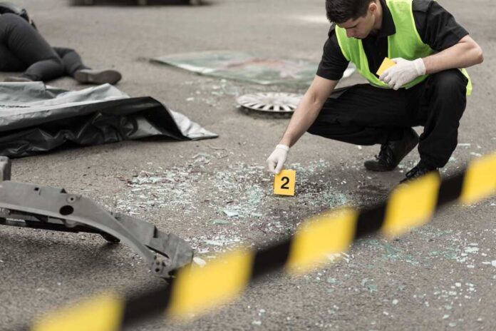 Police investigating crime scene with evidence marker and body bag.