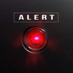 Red alert light against black background, text ALERT.