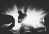 Silhouetted guitarist performing on stage with dramatic lighting.