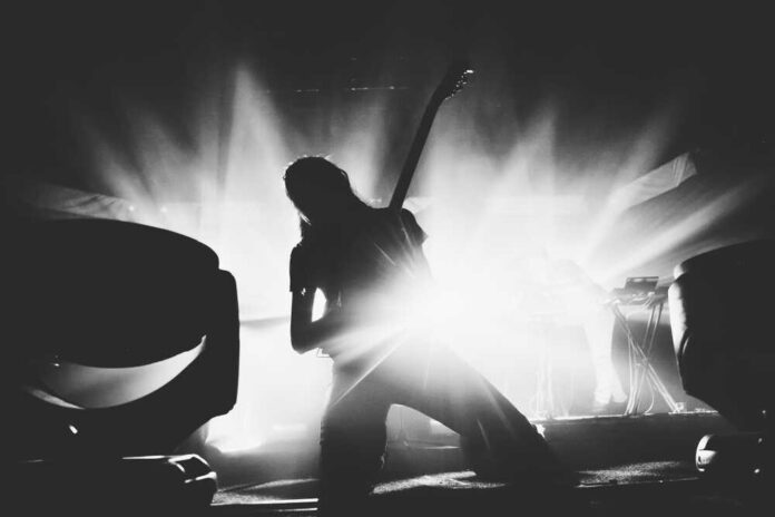 Silhouetted guitarist performing on stage with dramatic lighting.