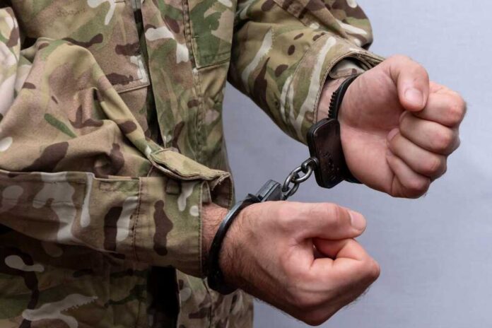 Person in military uniform handcuffed hands close up