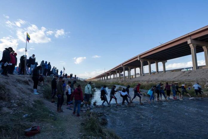 Migrants crossing river near bridge walkway at the US Mexico border