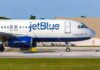 JetBlue airplane taxiing on airport runway.