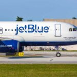 JetBlue airplane taxiing on airport runway.