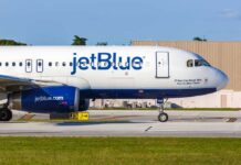 JetBlue airplane taxiing on airport runway.