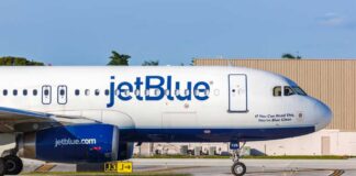 JetBlue airplane taxiing on airport runway.