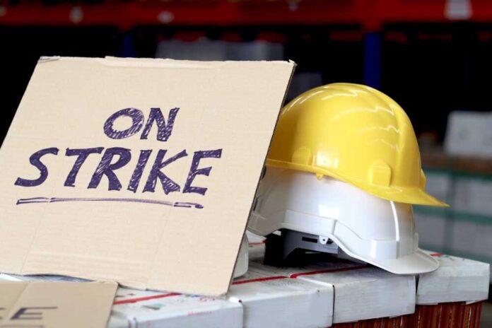 Sign reads On Strike near yellow hardhat