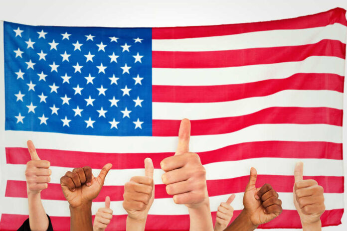 Thumbs up in front of American flag.