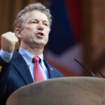 Rand Paul giving a passionate speech with fist raised.