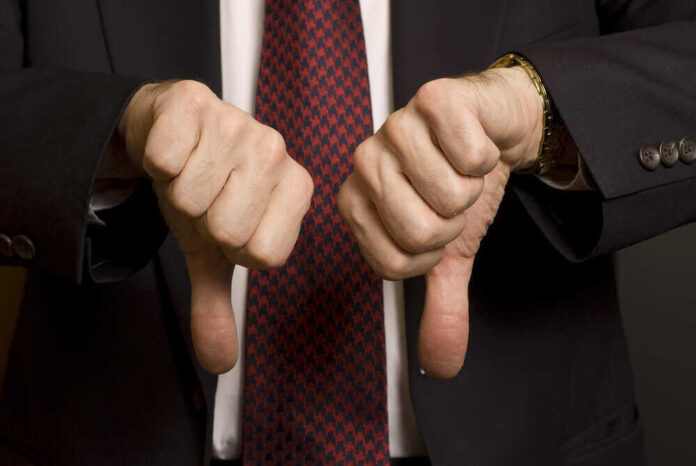 Two hands showing thumbs down in a suit.