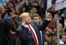 Man in suit gesturing at a crowded event.